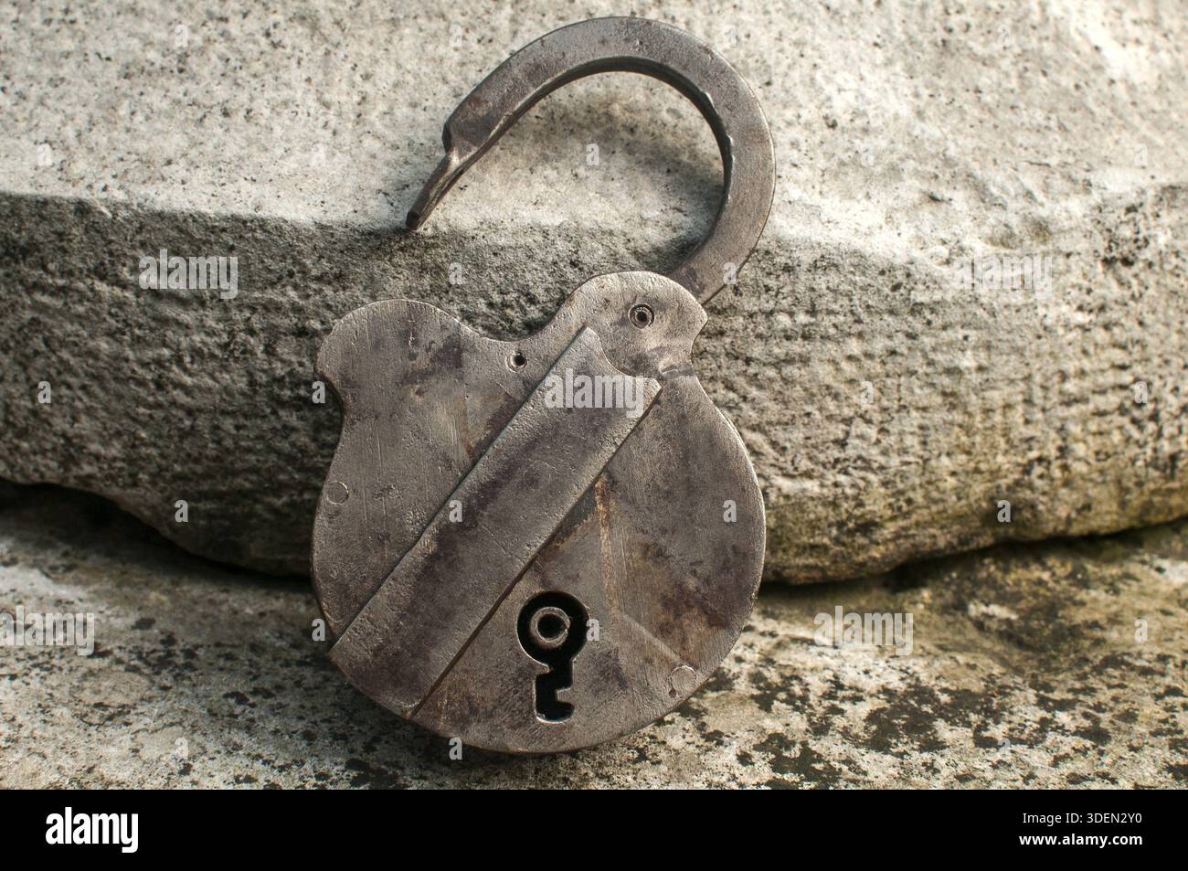 Old weathered grunge retro open padlock closeup on solid stone surface background Stock Photo