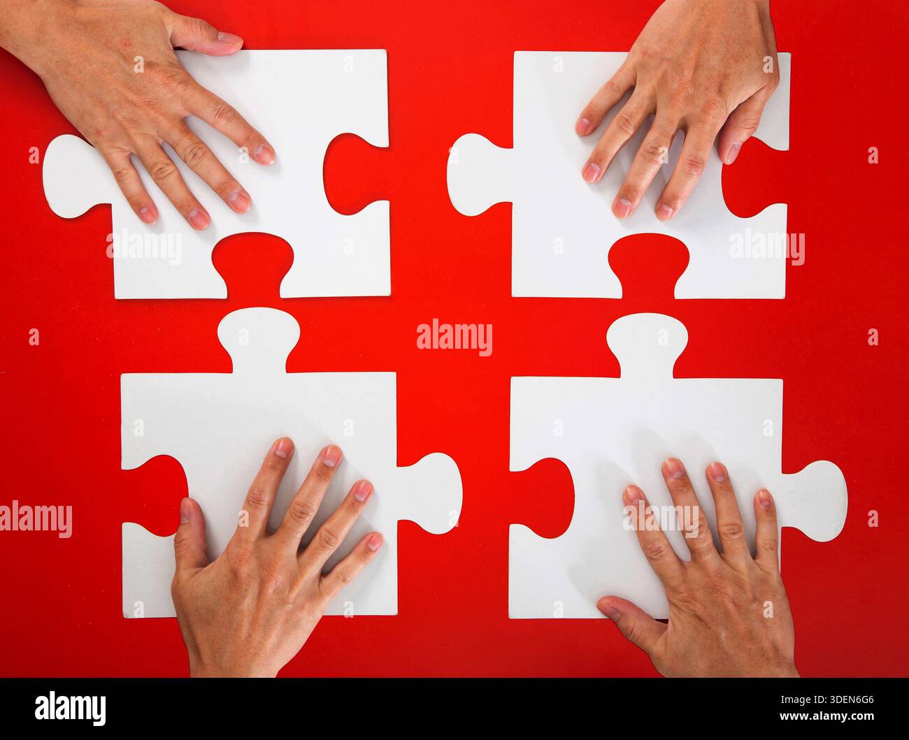 Hands collaborating to complete puzzle solving business problem Stock Photo
