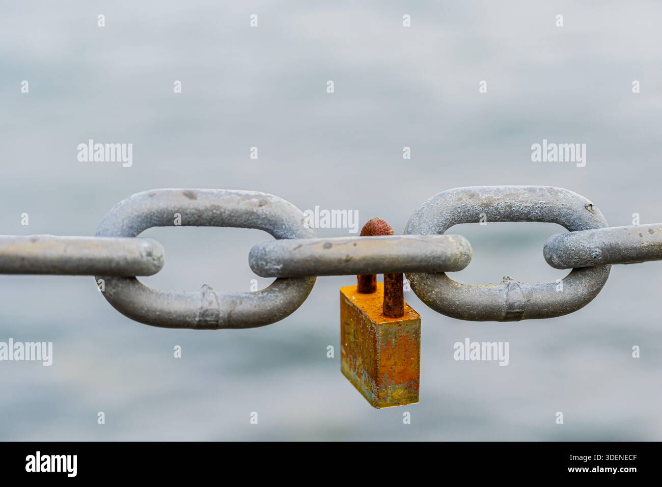 Rusted padlock hanging on a chain Stock Photo