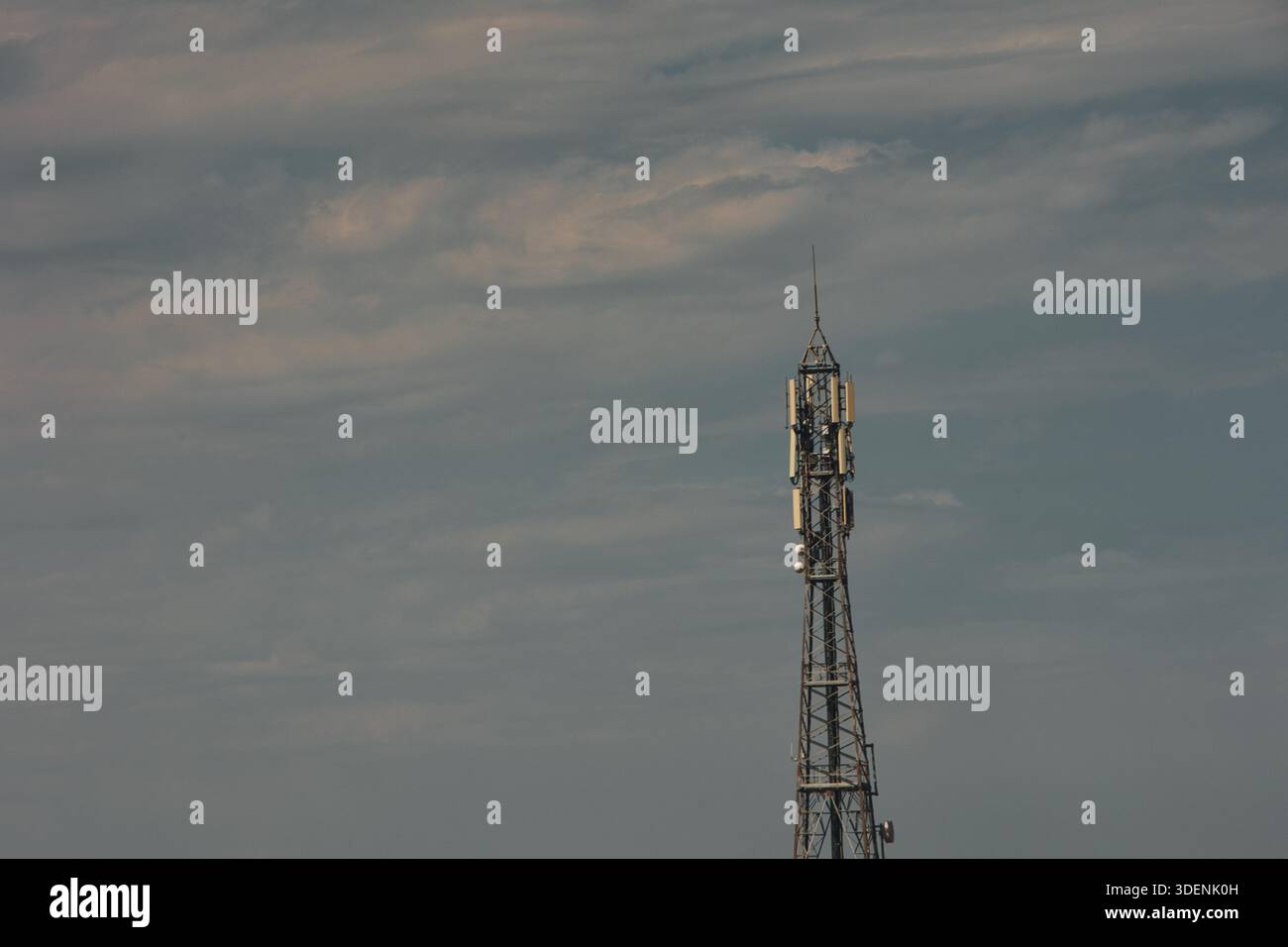 A high-voltage power transmission tower stands against a dramatic ...
