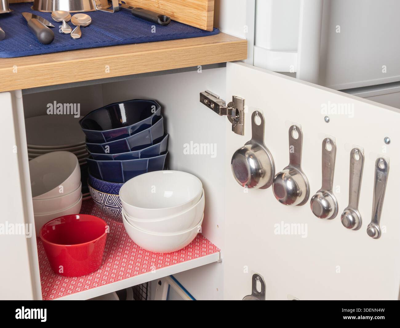 A kitchen cabinet holds stainless steel measuring cups and spoons on ...