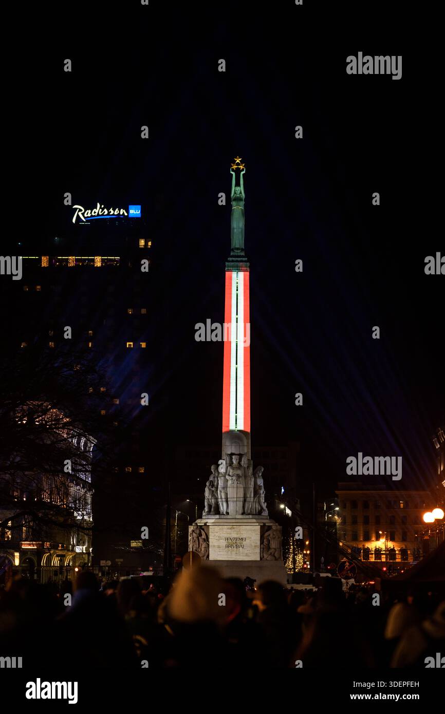 RIGA, LATVIA. 18th November 2025. Monument of Freedom illuminated in Latvian flag colors to honor Indendence Day of Latvia. Stock Photo