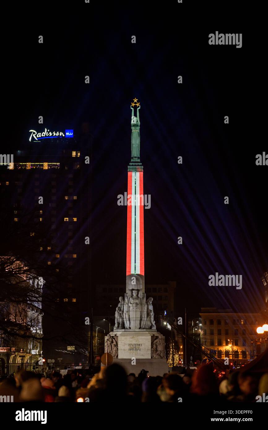 RIGA, LATVIA. 18th November 2025. Monument of Freedom illuminated in Latvian flag colors to honor Indendence Day of Latvia. Stock Photo
