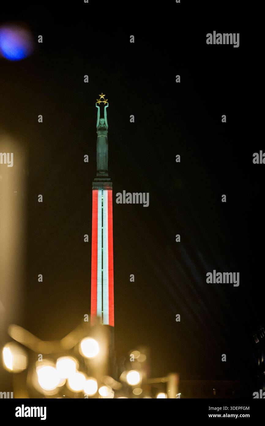 RIGA, LATVIA. 18th November 2025. Monument of Freedom illuminated in Latvian flag colors to honor Indendence Day of Latvia. Stock Photo