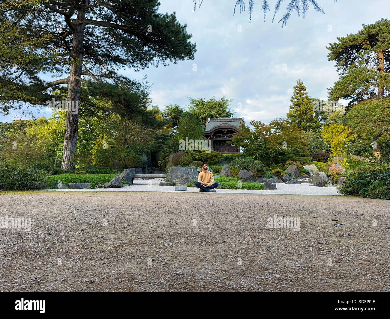 Person sitting in Japanese Landscape with gravel paths and trees, Royal Botanic Gardens Kew, UK. Stock Photo