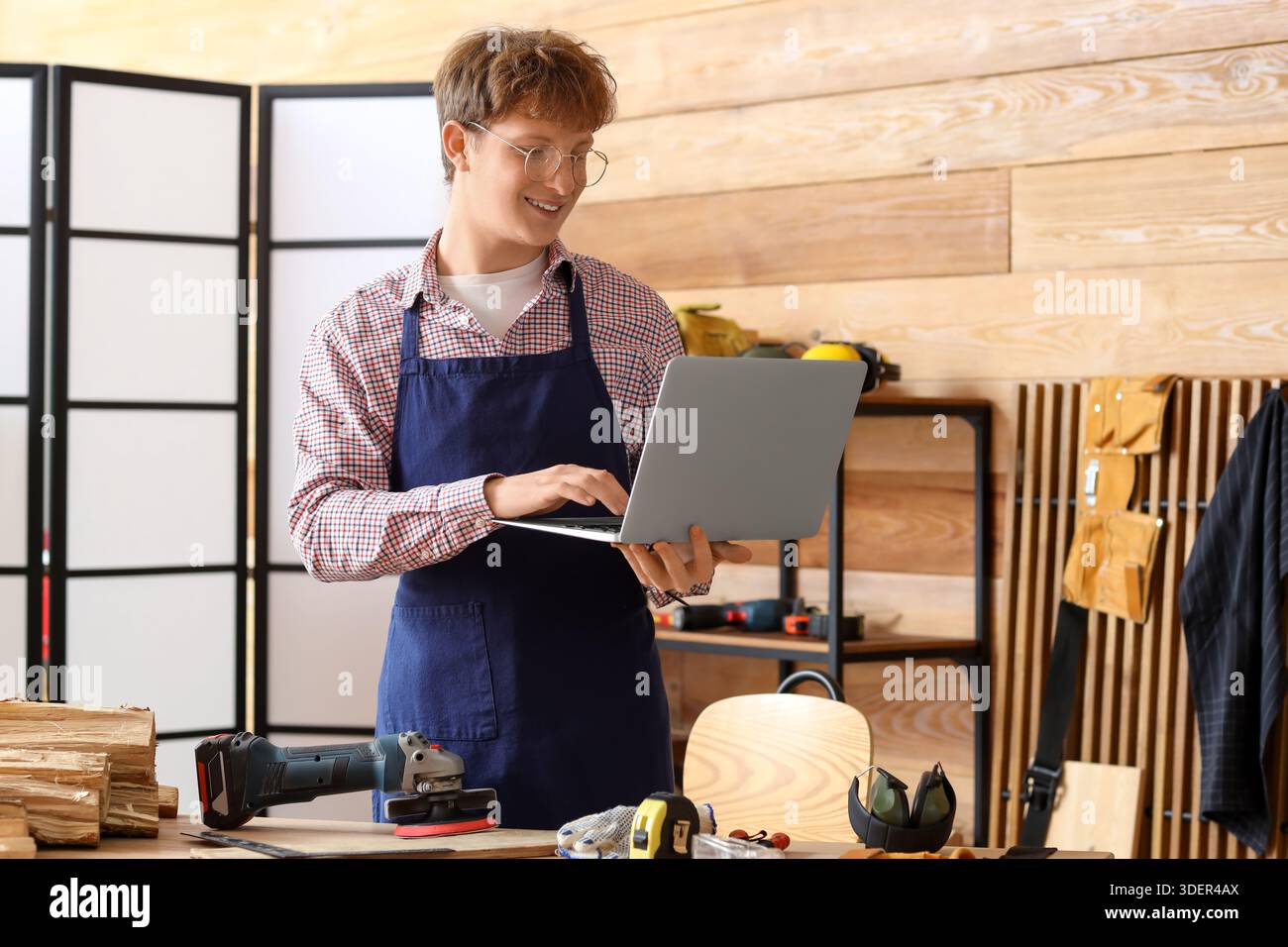 Young carpenter using laptop in workshop Stock Photo
