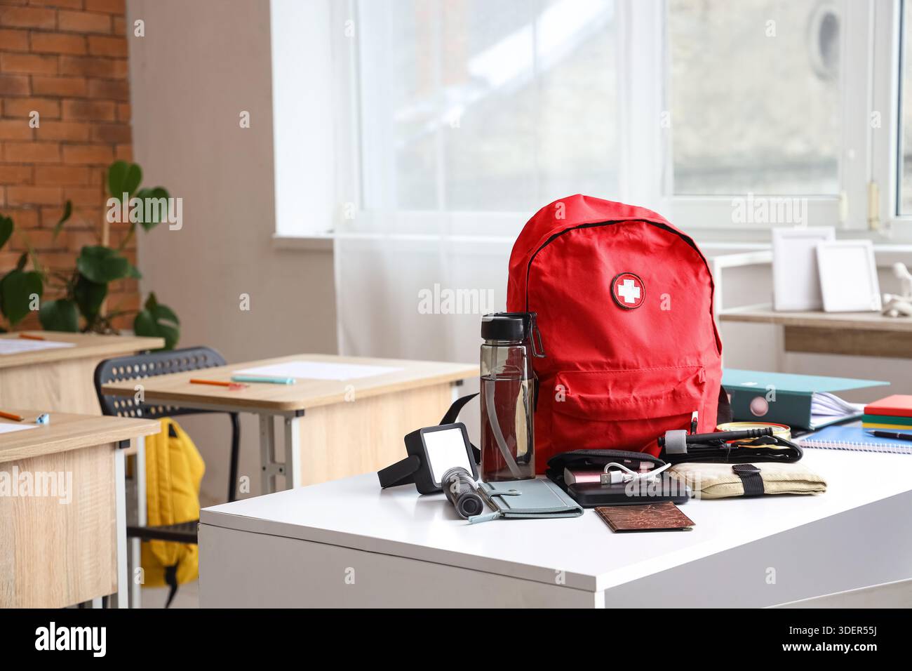 Emergency backpack with necessities on table in classroom Stock Photo