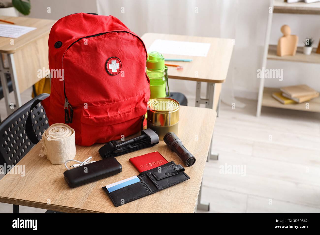 Emergency backpack with necessities on desk in classroom Stock Photo