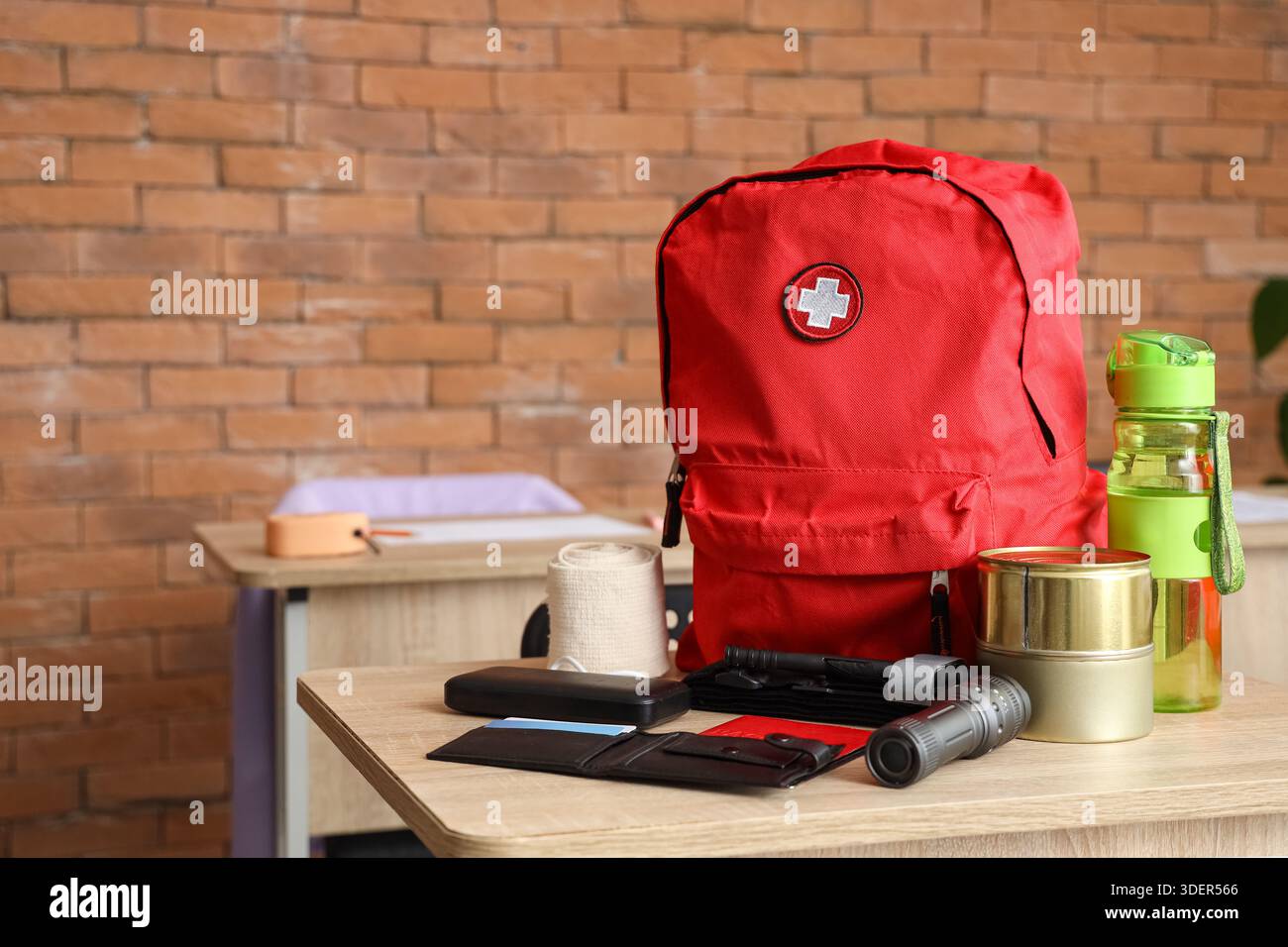 Emergency backpack with necessities on desk in classroom Stock Photo