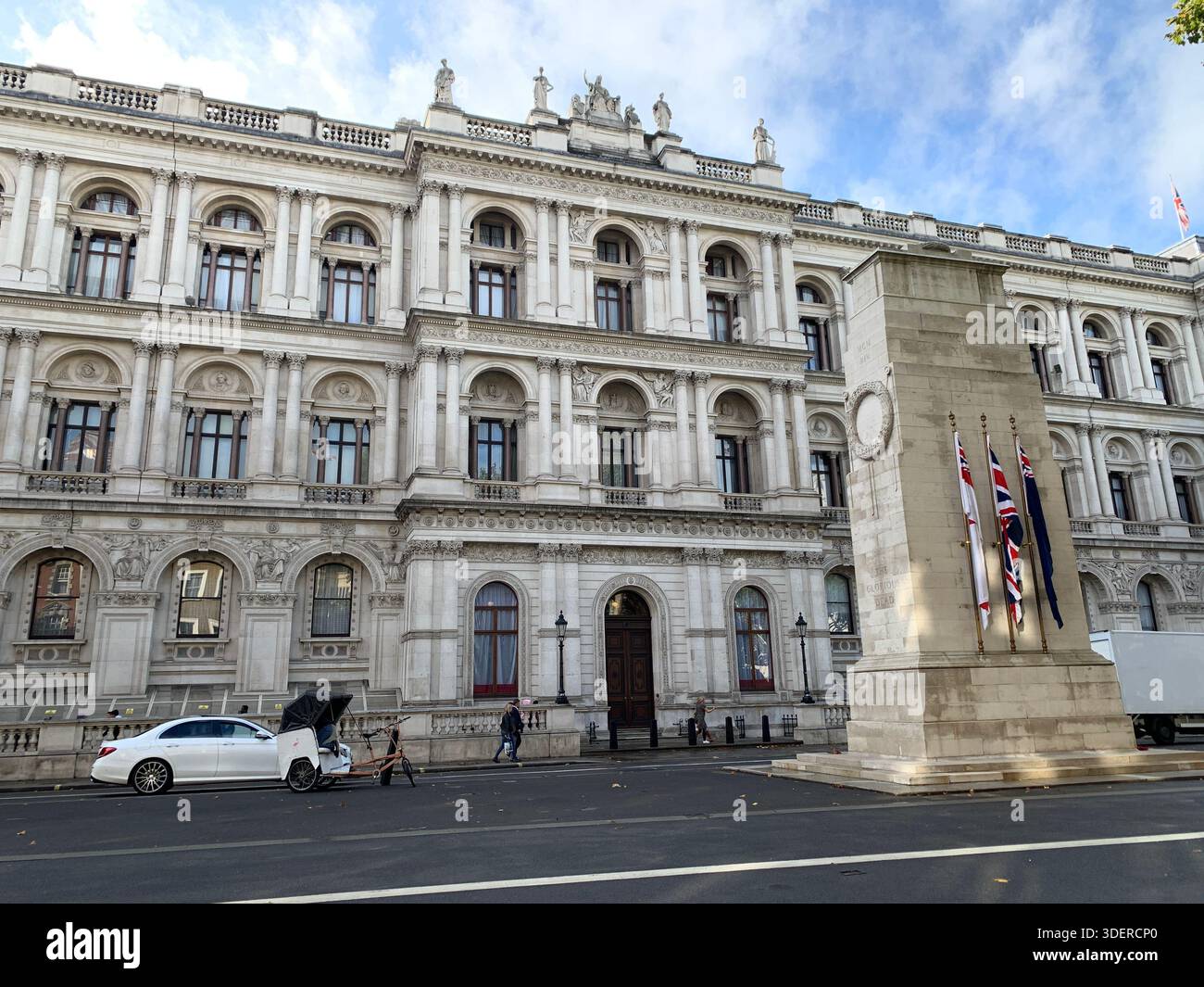 LONDON, UK, October 22, 2019, London Whitehall street view with a grand stone government facade, the Cenotaph with flags, pedestrians, a car and a Stock Photo