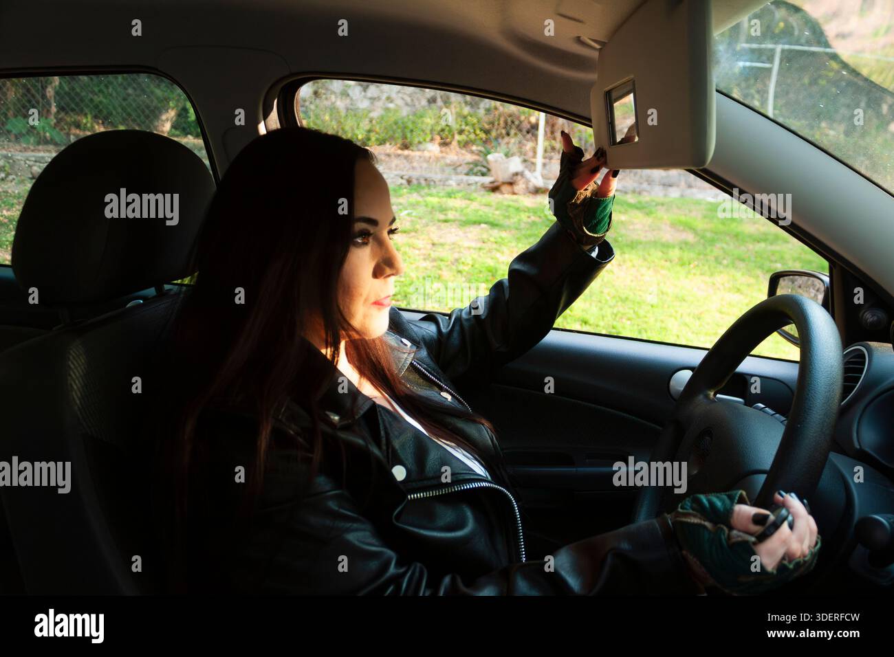 Woman adjusting sun visor while driving car at sunset Stock Photo