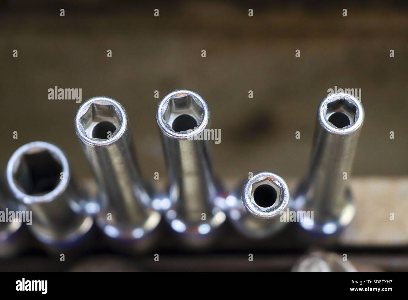 Close up view of shiny chrome socket wrench set head on blurry wooden background with industrial concept, useful sturdy steel tool kit prepared for pr Stock Photo