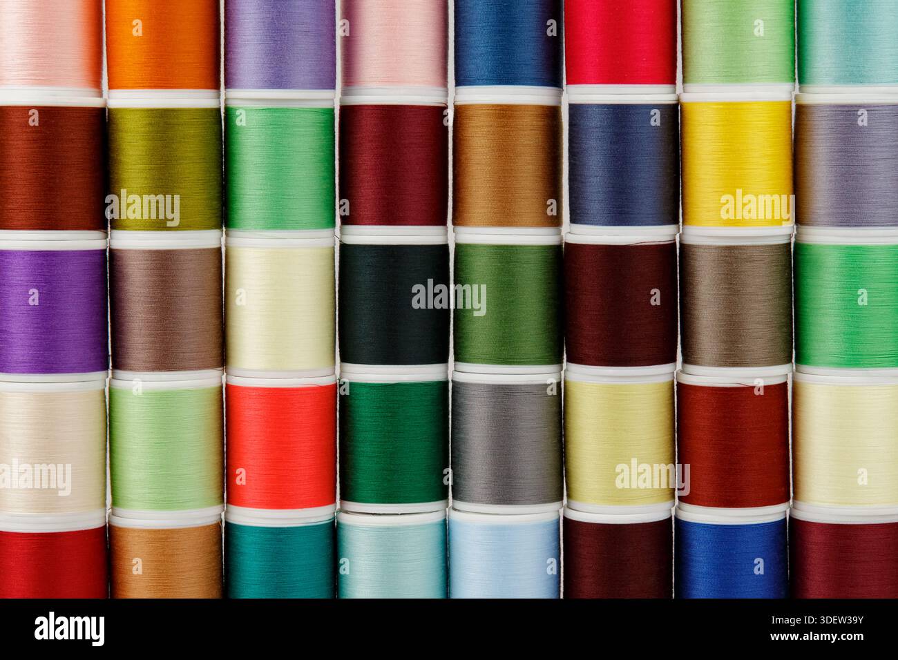 Colored spools of thread in an orderly row. Stock Photo
