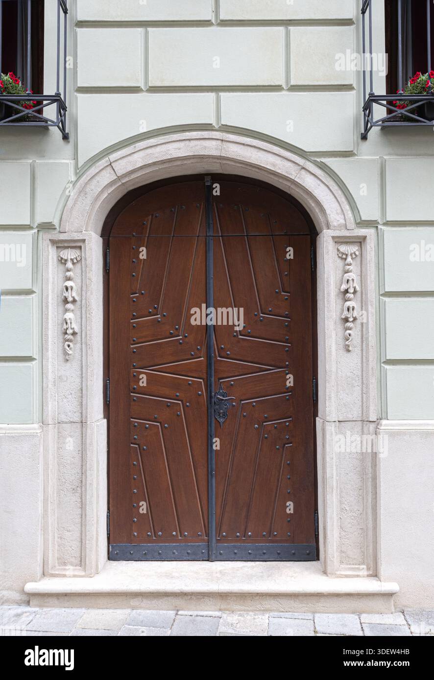 Elaborate geometric pattern on vintage wooden doors with a carved stone archway and facade Stock Photo