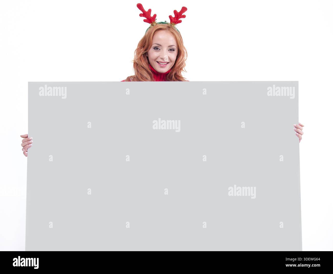 Charming smiling girl with christmas sweater holding blank paper sheet Stock Photo