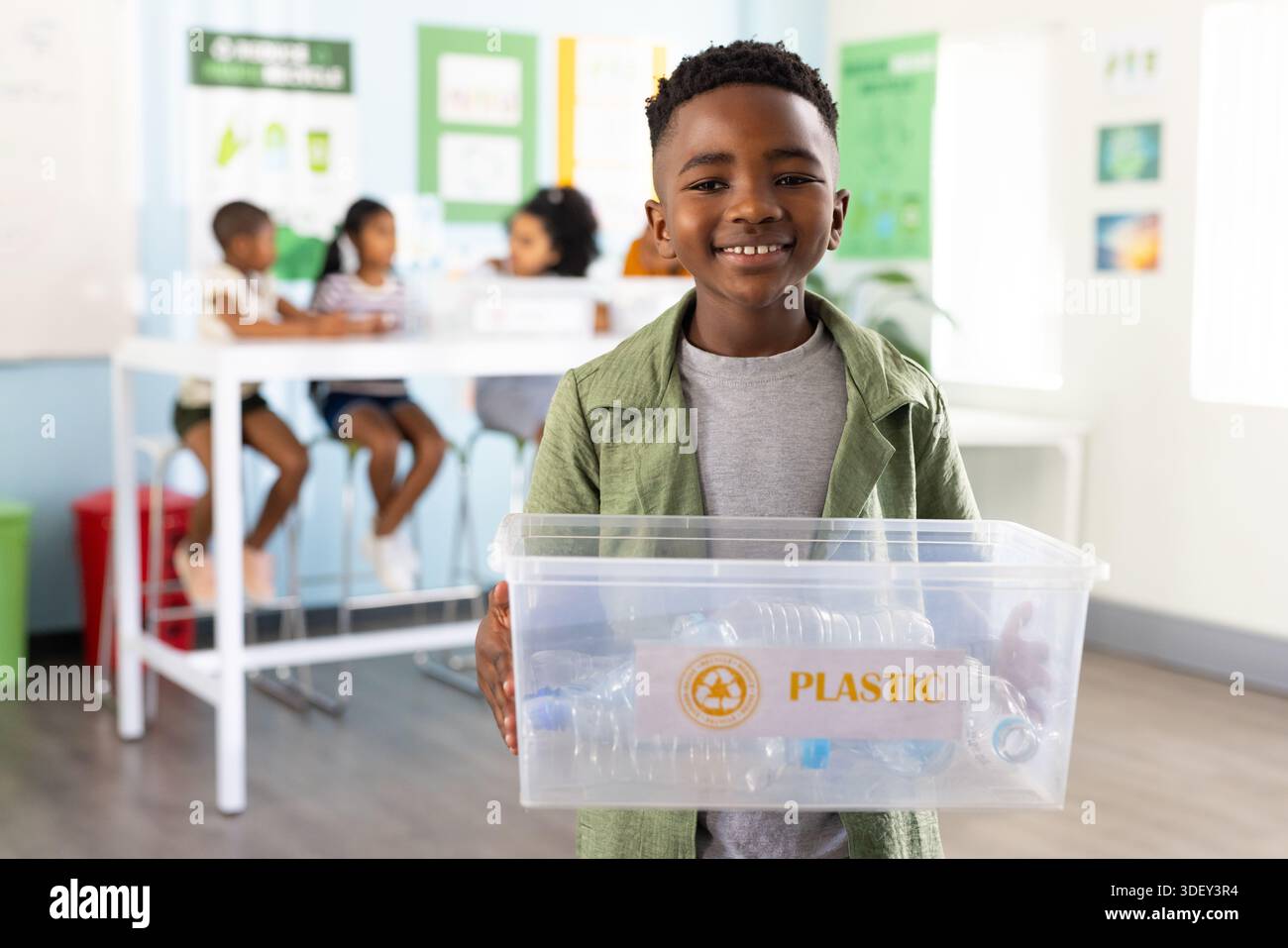 African American youth students holding bin labeled PLASTIC with empty bottles in classroom Stock Photo
