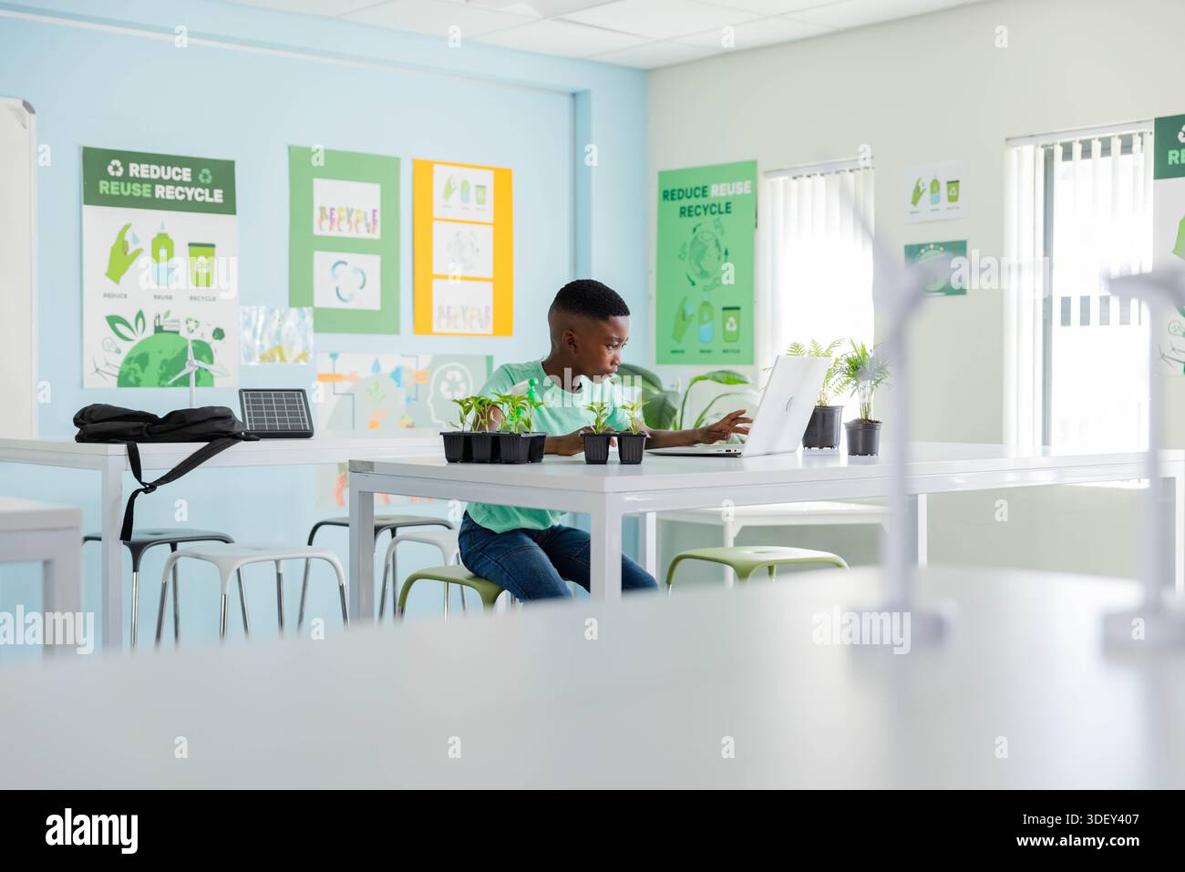 African American youth male studying plants and using laptop in classroom with solar panel Stock Photo