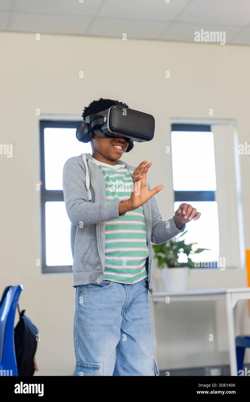 VR headset and over-ear headphones are resting on white table with potted plant and backpack Stock Photo
