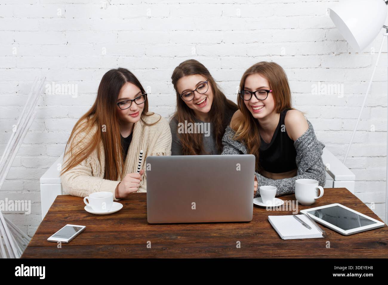 Three Friends Share a Moment While Using a Laptop in a Modern Workspace Stock Photo