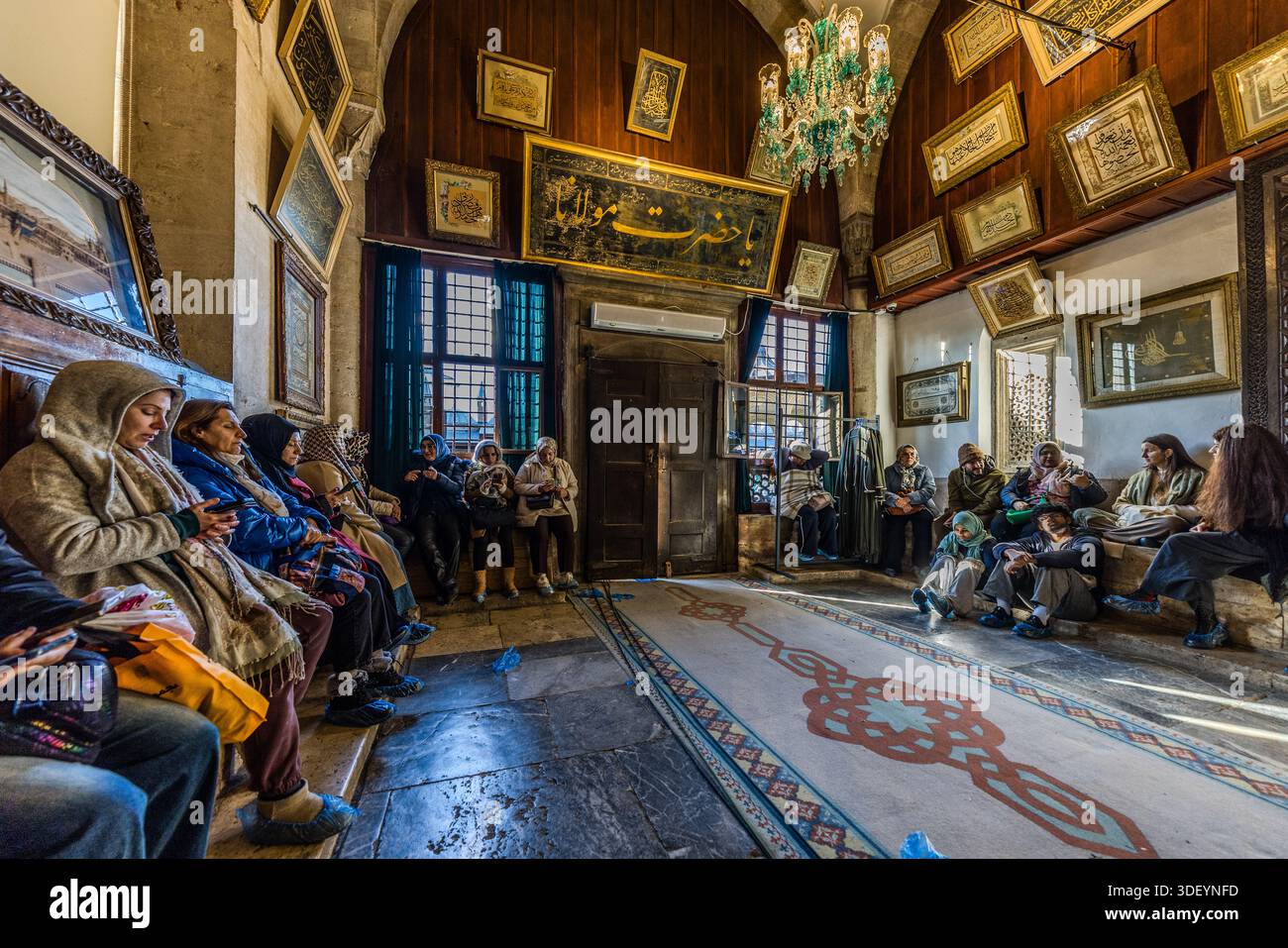 The Tilavet Room (Tilavet Odası) in the Mevlana Museum (Mevlânâ Müzesi) leads to the tomb chamber of Jalāl ad-Dīn ar-Rūmī. Until the building became a museum, the Koran was recited and sung here without interruption. Pilgrims now use their smartphones for their own devotions. The museum is the mausoleum of the Sufi mystic Rumi (Jalāl ad-Dīn ar-Rūmī, 1207–1273), with an adjoining mosque and former dervish lodge; the turquoise dome built over his grave in 1274 is considered a symbol of Konya. Karatay, Konya, Turkey. Stock Photo