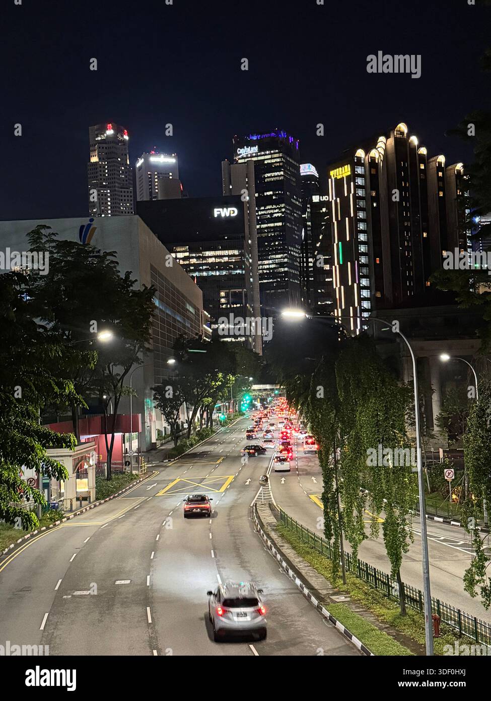A vibrant city street at night with illuminated buildings, flowing traffic, and glowing signage - Smartphone Captured Stock Image