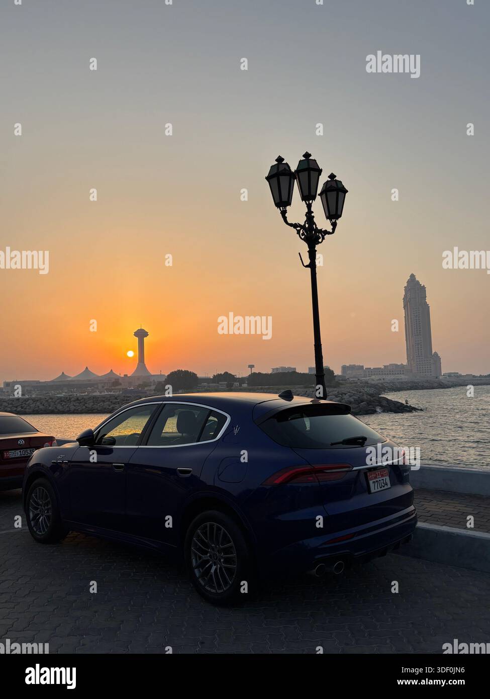 Golden hour in Abu Dhabi — a luxury SUV rests by the waterfront as the skyline glows in silhouette - Smartphone Captured Stock Image