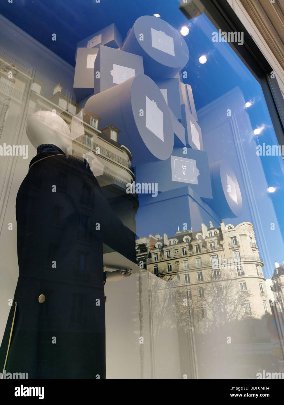 Window of Dior store in Avenue Montaigne, Paris, France, with mannekin carrying Dior boxes and reflections of surrounding buildings. - Smartphone Captured Stock Image
