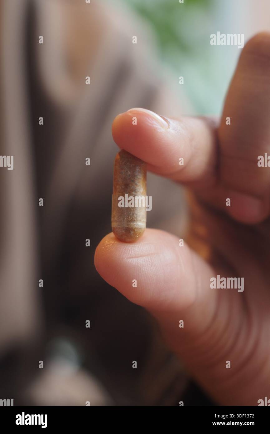 Holding a capsule with one hand in a close view Stock Photo