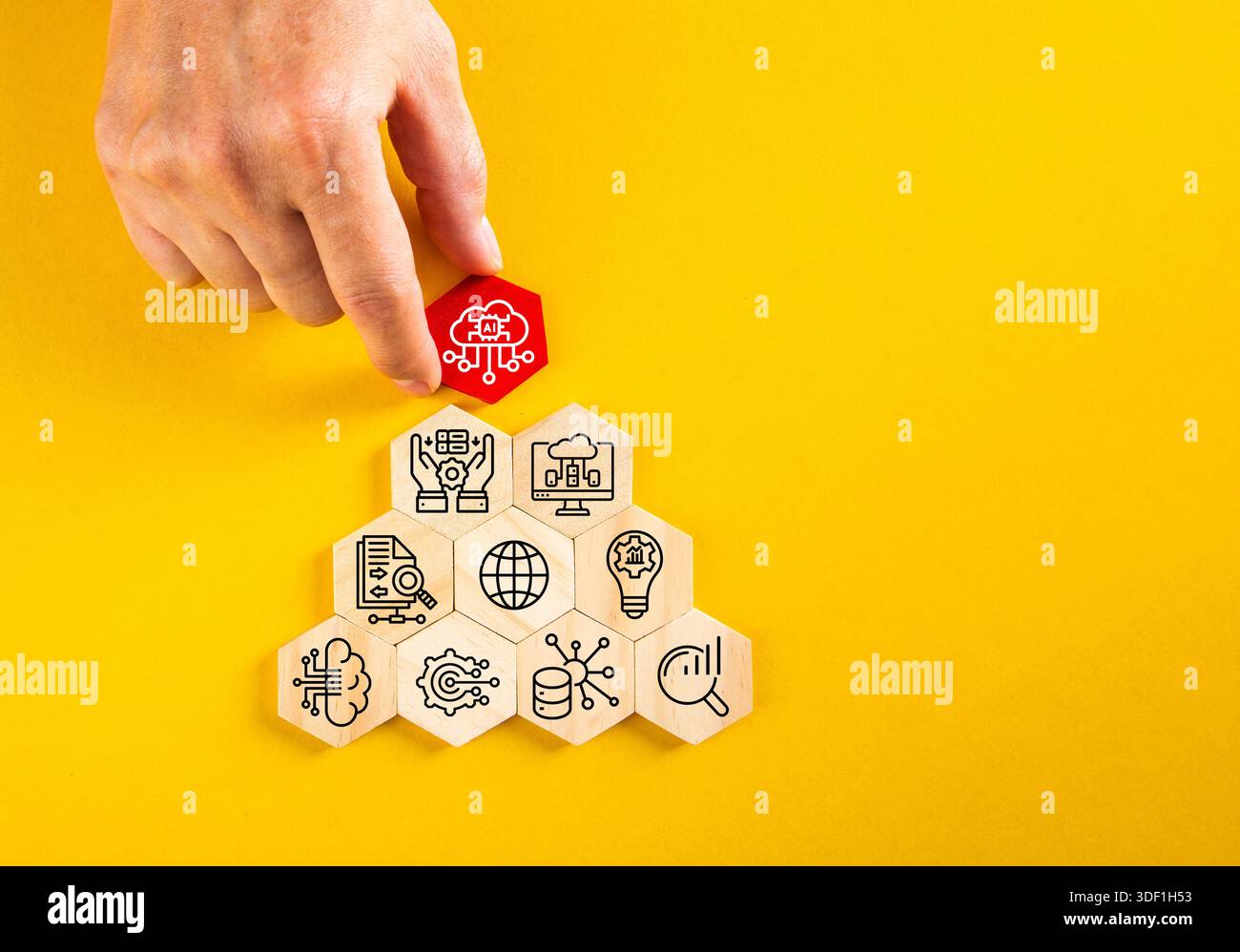Human hand adding artificial intelligence cloud icon to a stack of technology concept hexagons Stock Photo