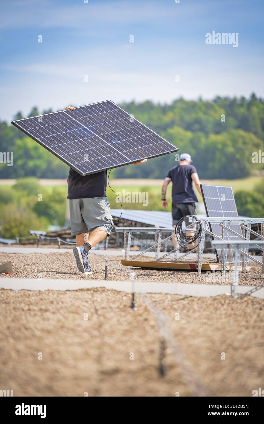 Solar Plan Ride Workers install solar panels with cables in an open field under a blue ...