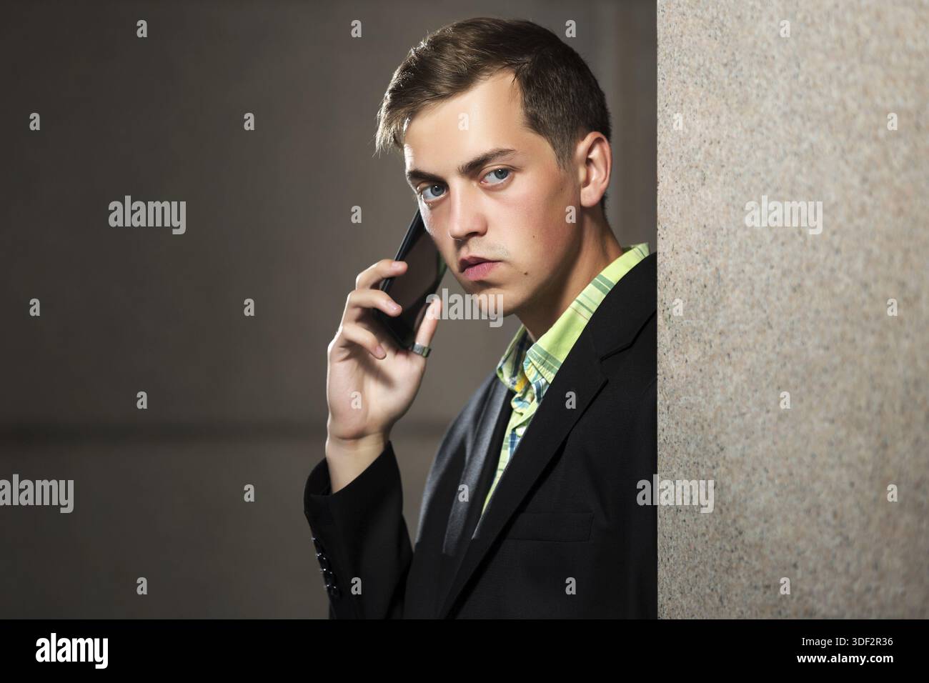 Young man calling on mobile phone at the wall Stock Photo