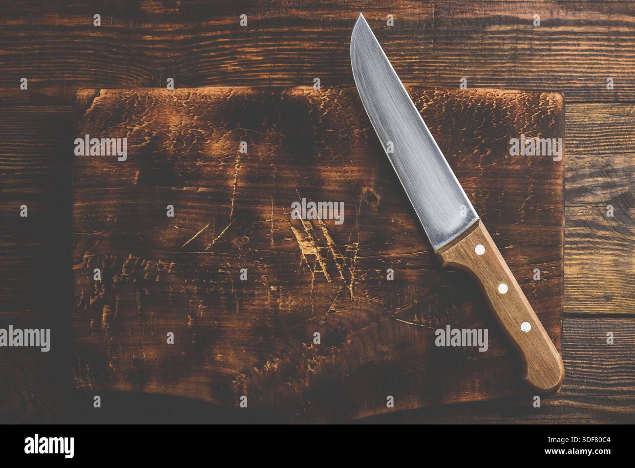 Knife over rustic wooden cutting board Stock Photo