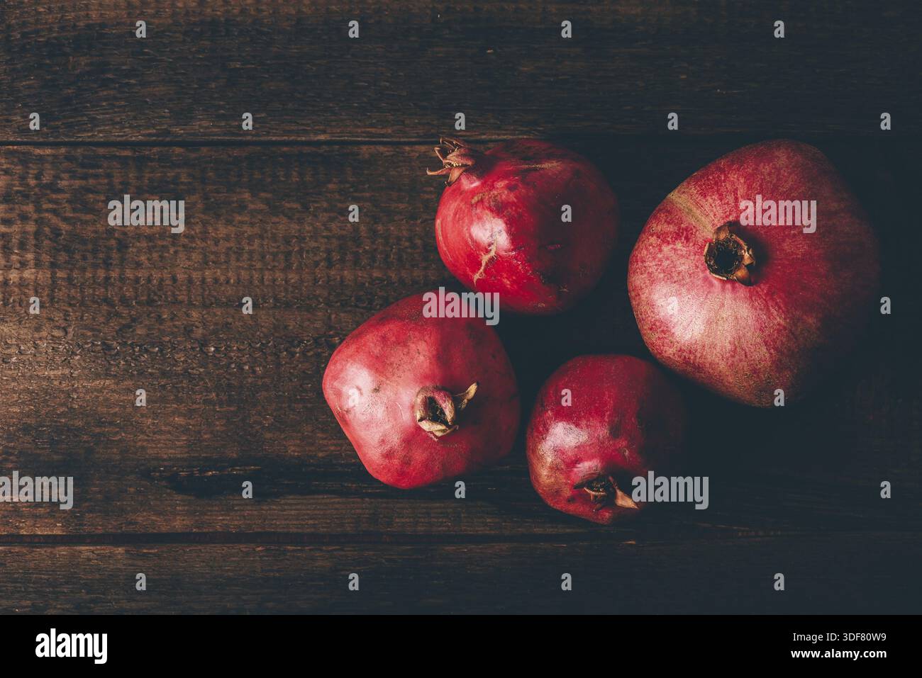 Four ripe pomegranate on rustic wooden table Stock Photo
