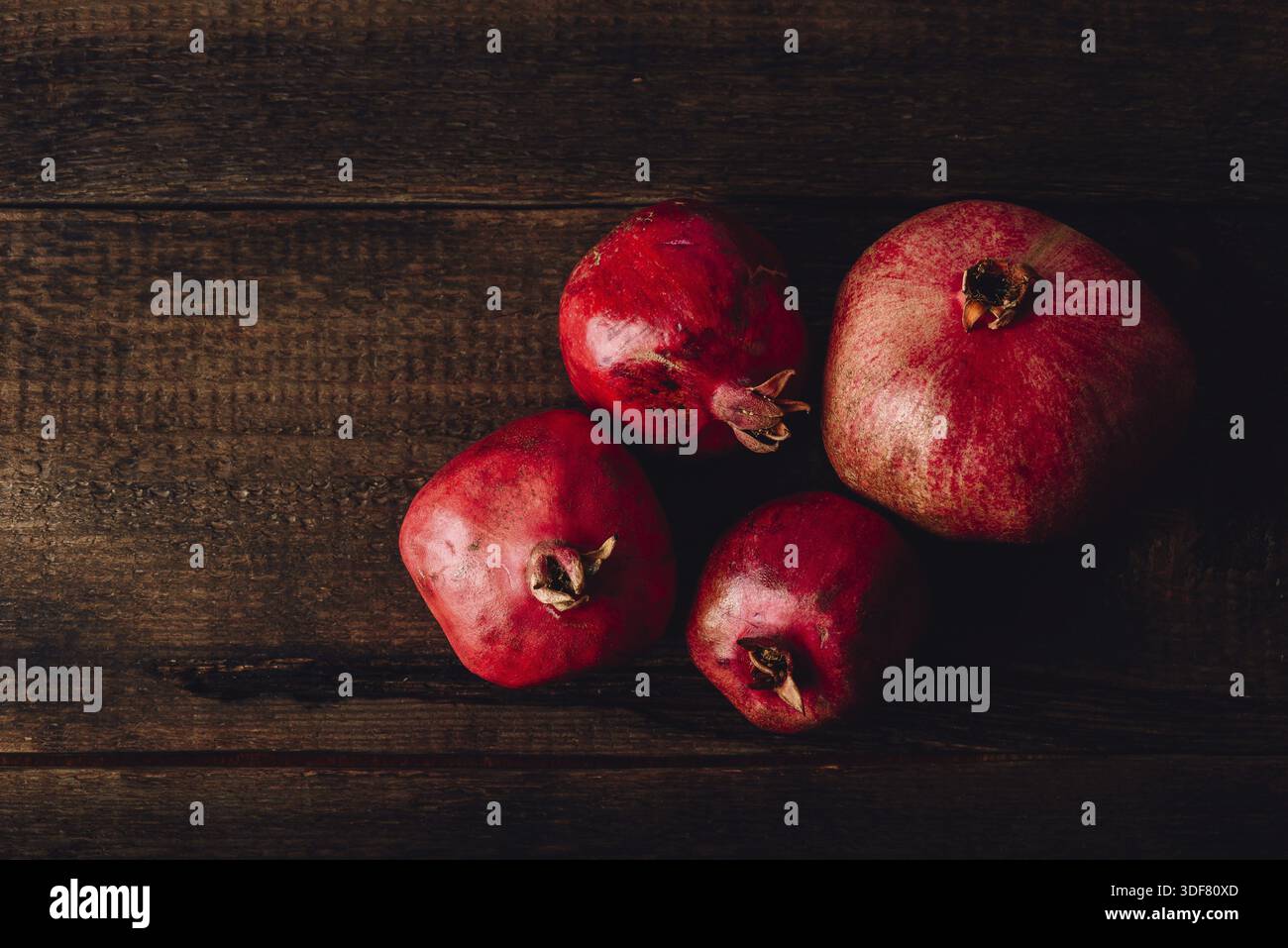 Four ripe pomegranate on rustic wooden table Stock Photo