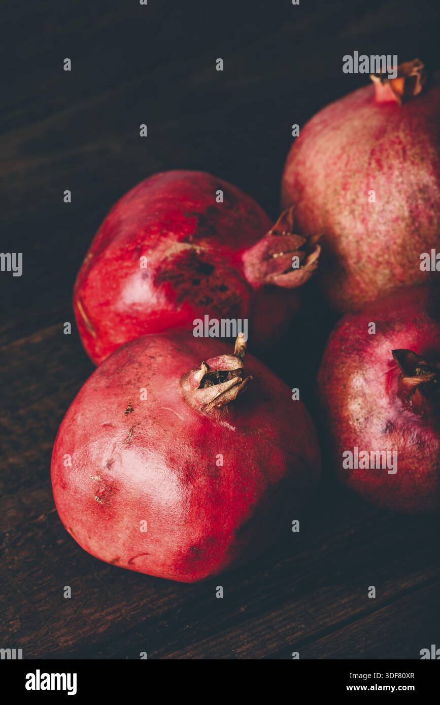 Four ripe pomegranate on rustic wooden table Stock Photo