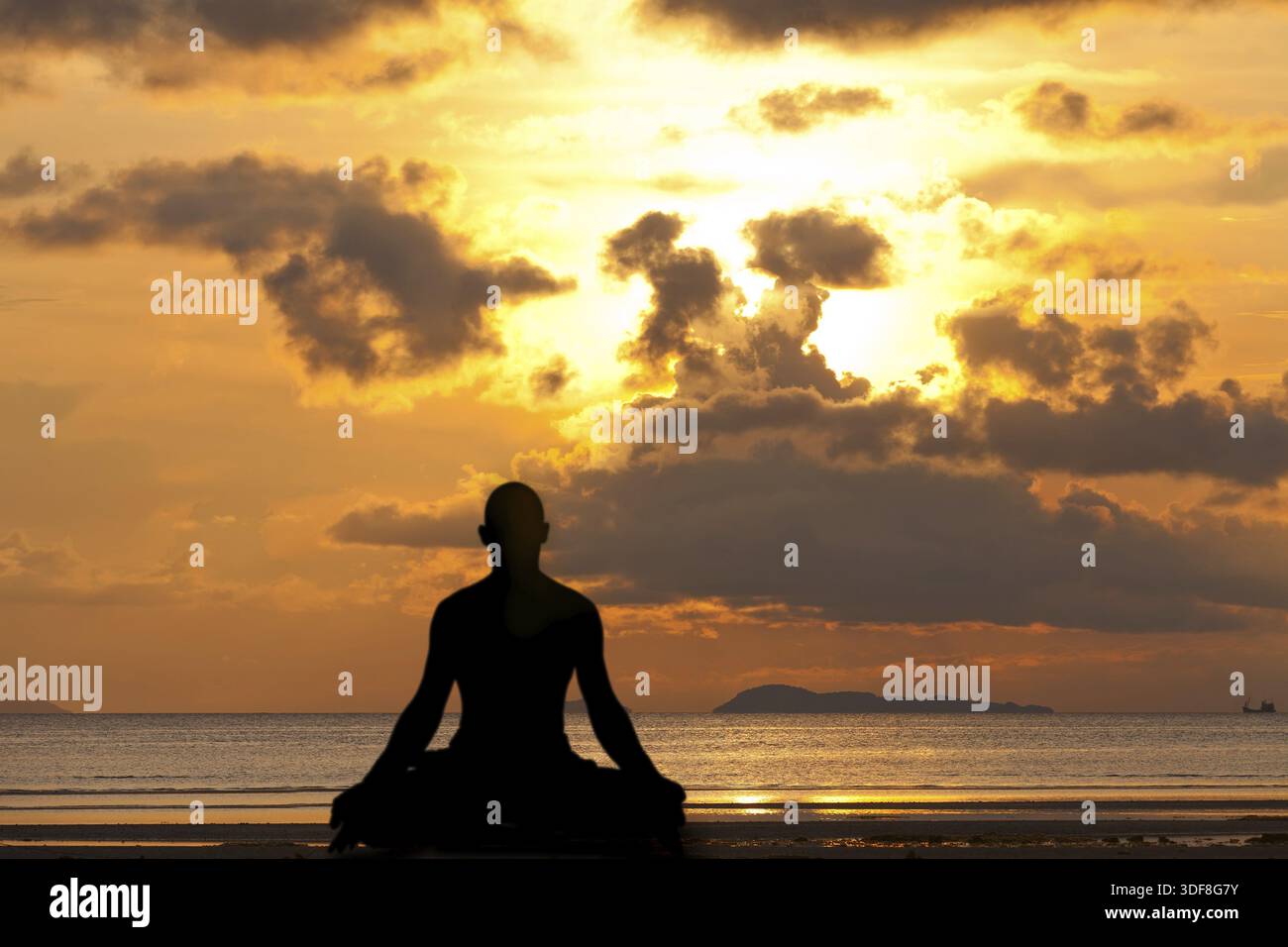 Man silhouette doing yoga exercise at sunset beach Stock Photo
