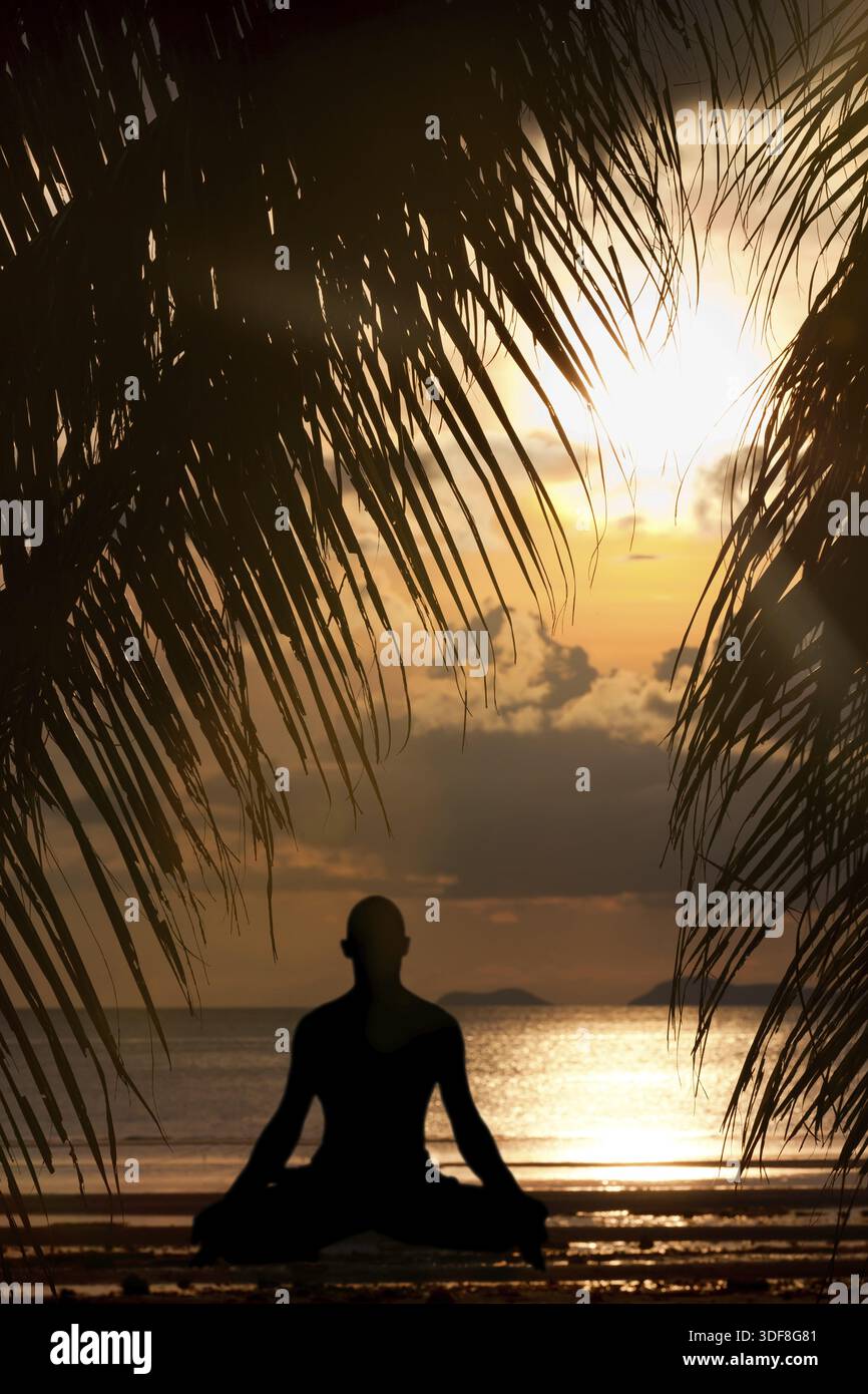 Man silhouette doing yoga exercise at sunset beach Stock Photo
