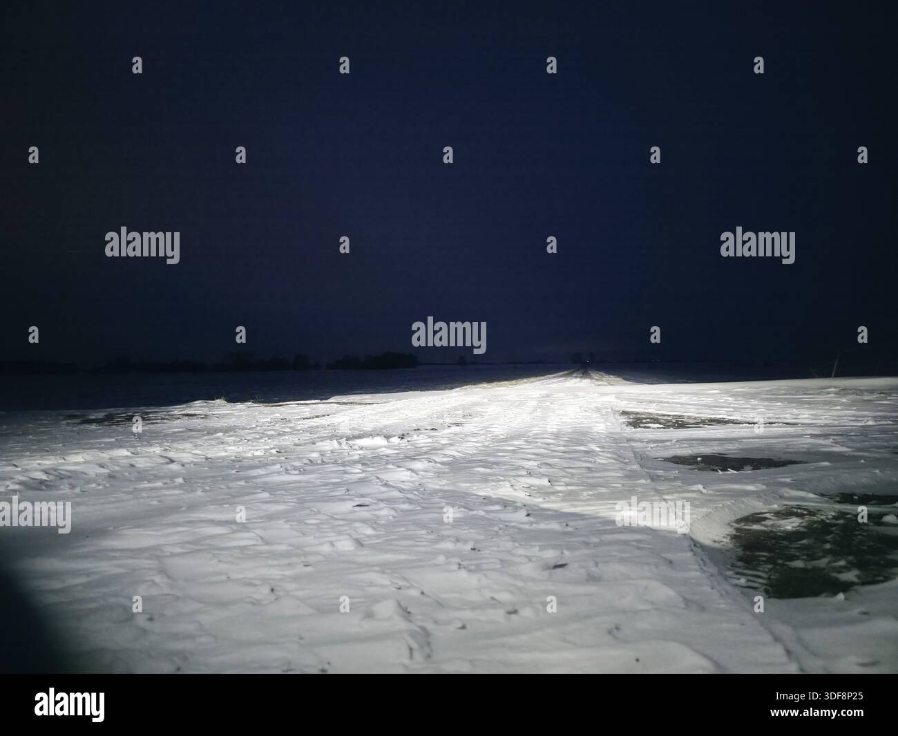 Snowy road in the dark, creates a feeling of cold and abandonment, winter and snow in 27798 Hude, Holle, Nieddersachsen, Germany Stock Photo