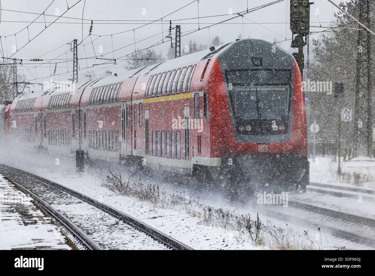 RegionalExpress RE on the road through a winter landscape in snowfall. A train on the line in the Deutsche Bahn AG rail network. Amstetten, Baden-Wuer Stock Photo
