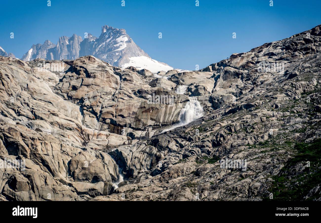 Rocky mountain landscape with a waterfall and snowy peaks. Stock Photo