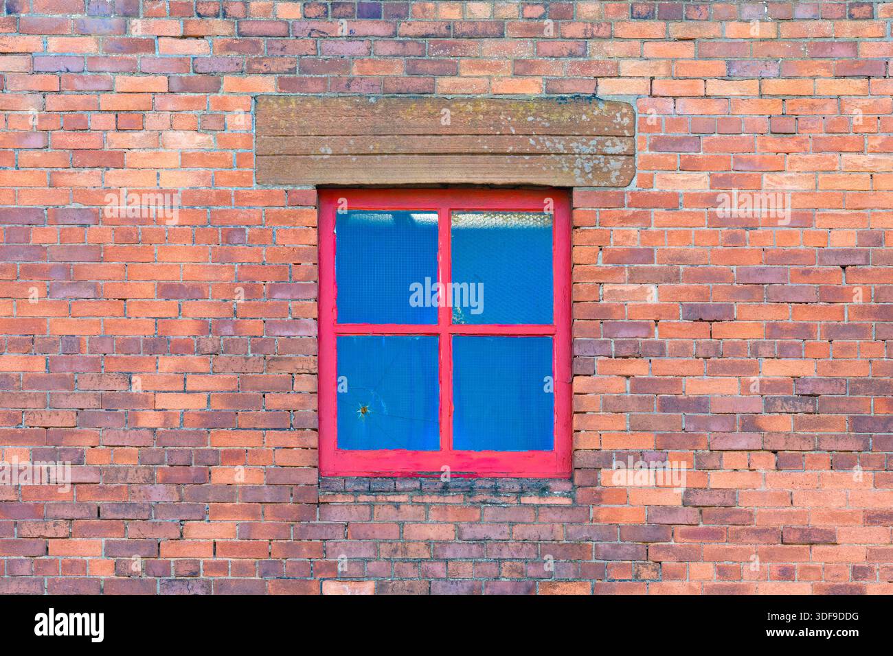 Red window frame in a brick wall, UK Stock Photo