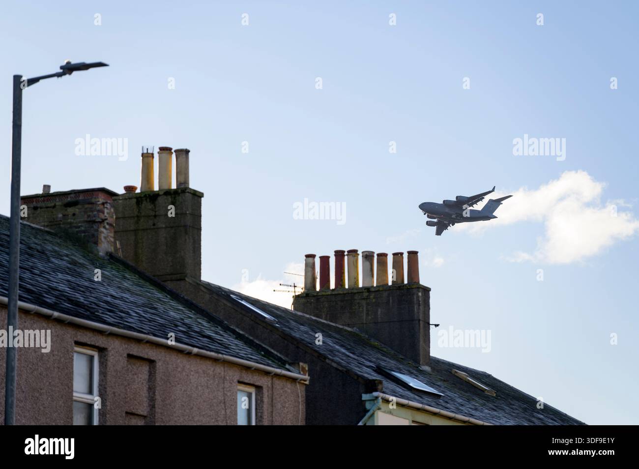 RAF Boeing C-17A Globemaster III flying low over house rooftops in Troon on the approach to Glasgow Prestwick Airport, South Ayrshire, Scotland, UK Stock Photo