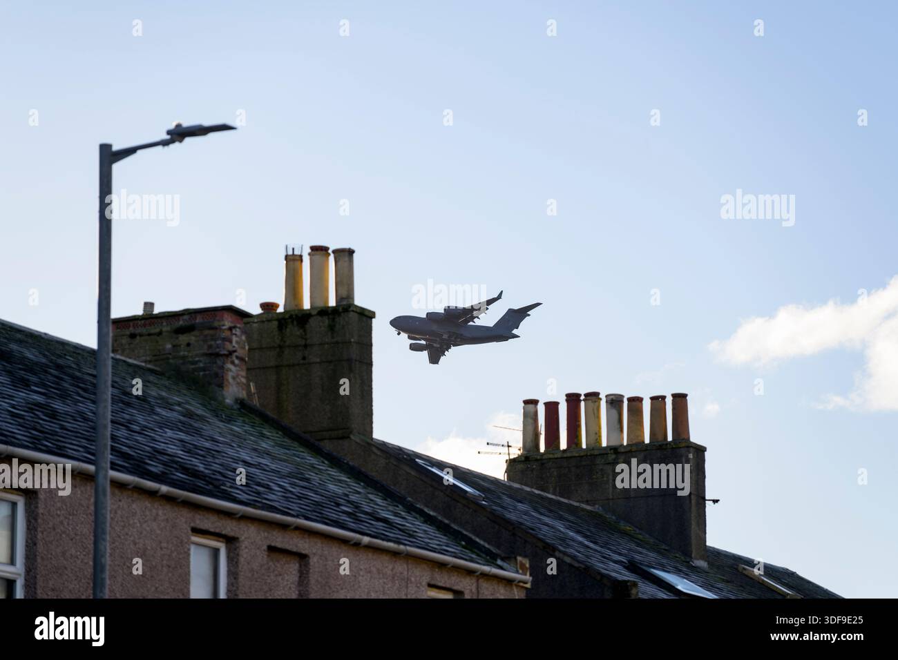 RAF Boeing C-17A Globemaster III flying low over house rooftops in Troon on the approach to Glasgow Prestwick Airport, South Ayrshire, Scotland, UK Stock Photo