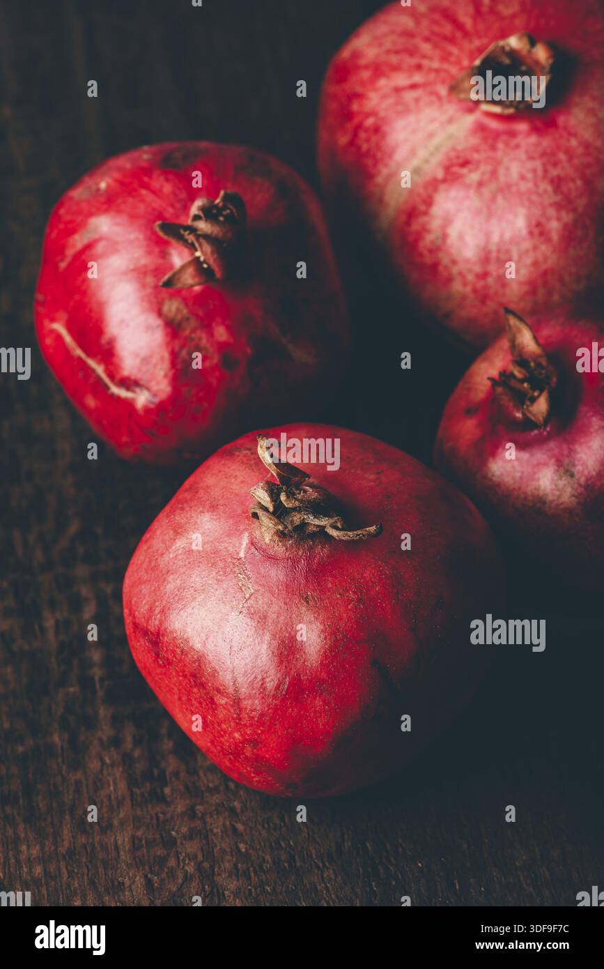Four ripe pomegranate on rustic wooden table Stock Photo