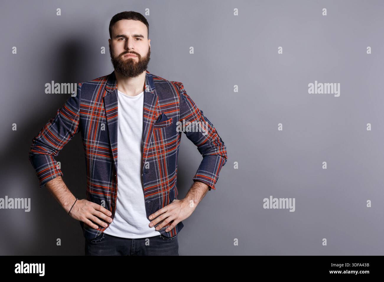 Serious bearded man posing with hands on hips Stock Photo