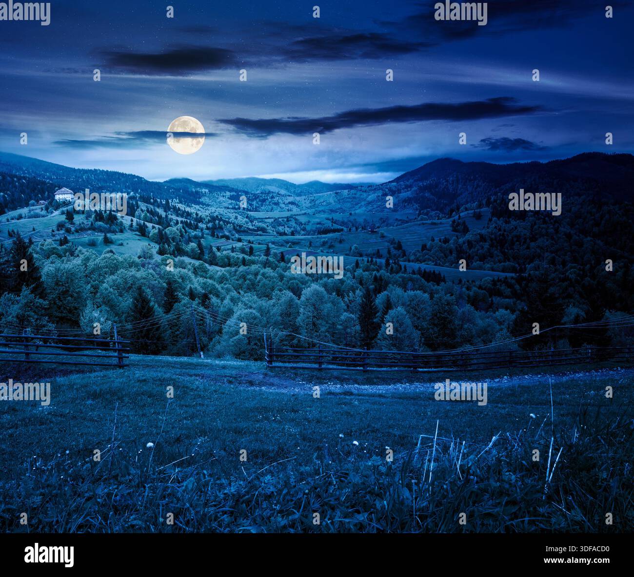 wooden fence in mountains in full moon light. alpine countryside in spring. cloudy sky. backdrop for fiction art or mystery concepts Stock Photo