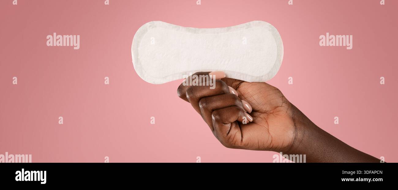 Woman Holding a Sanitary Pad Against a Pink Background During a Health Awareness Campaign Stock Photo