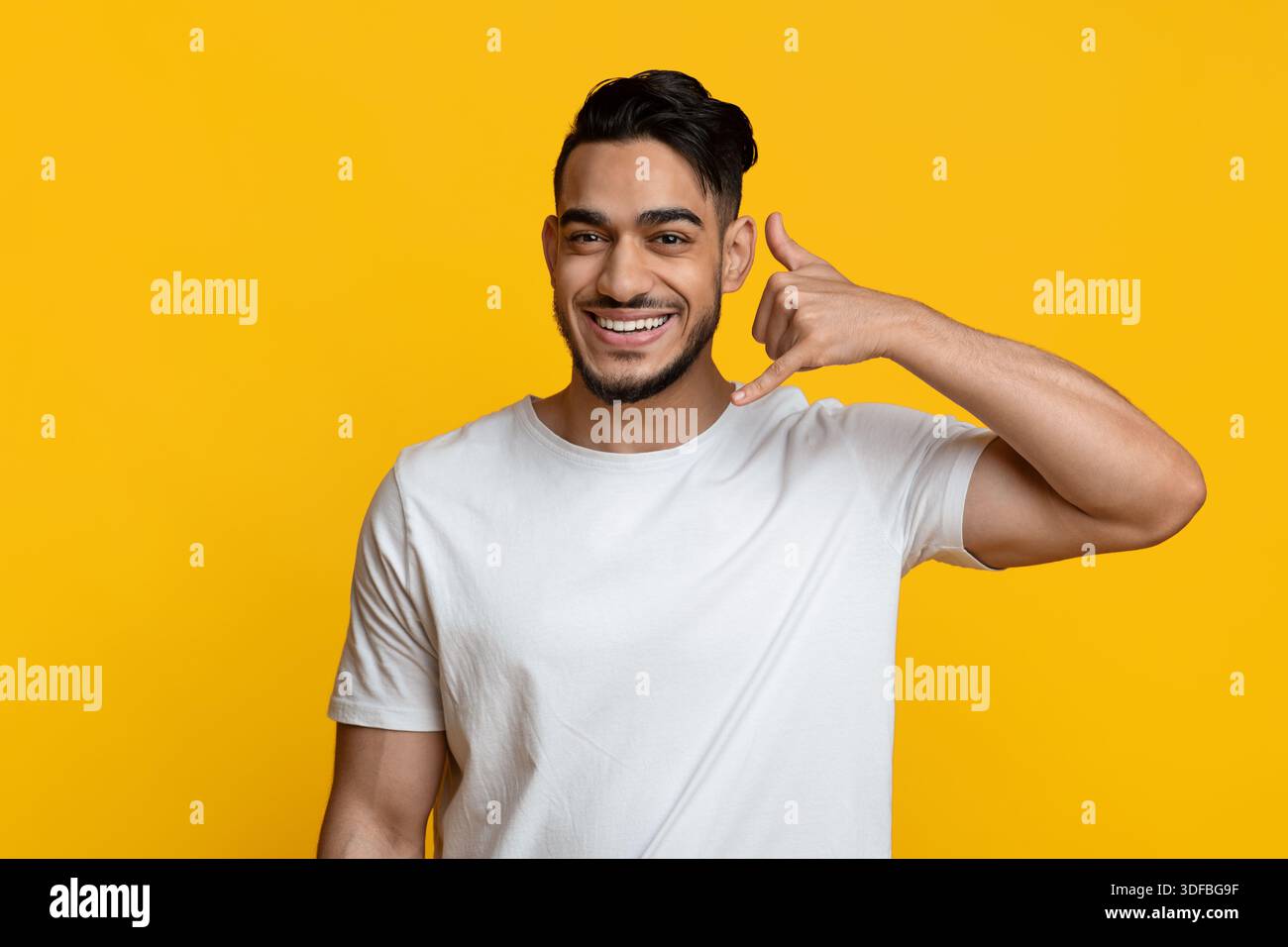 Cheerful middle eastern young man showing call me gesture Stock Photo