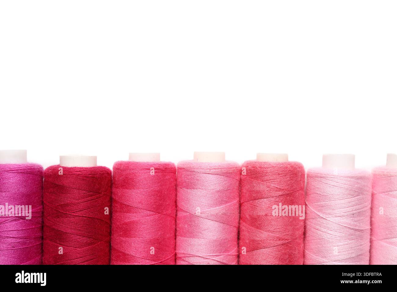 Spools of pink thread on white background Stock Photo