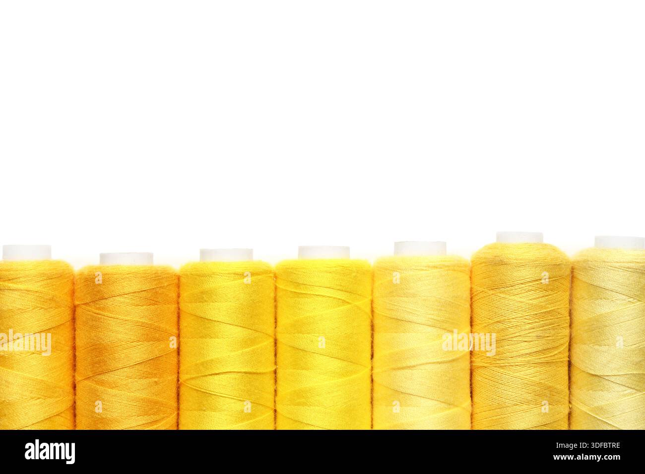 Spools of yellow thread on white background Stock Photo